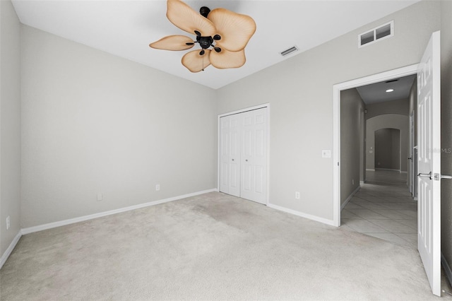 unfurnished bedroom featuring ceiling fan, a closet, and light colored carpet