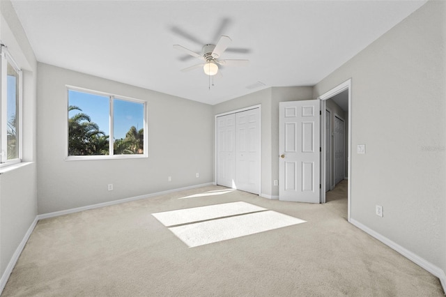 unfurnished bedroom featuring multiple windows, a closet, ceiling fan, and light colored carpet