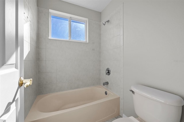 bathroom featuring tiled shower / bath combo and toilet