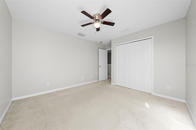 unfurnished bedroom featuring ceiling fan, a closet, and light carpet