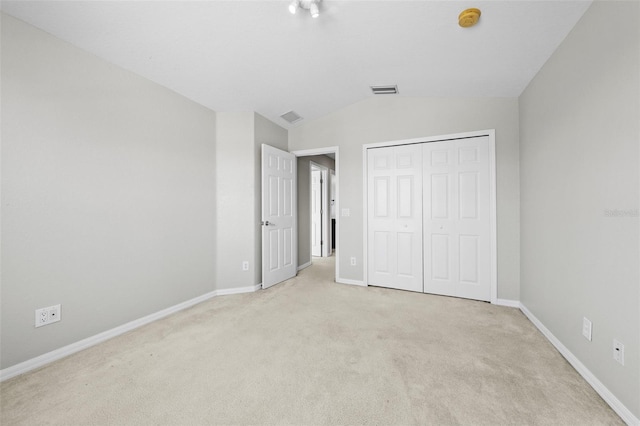 unfurnished bedroom featuring a closet, light colored carpet, and vaulted ceiling