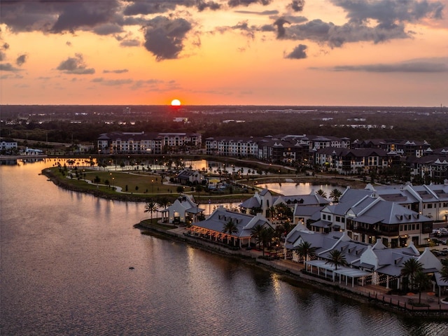 aerial view at dusk featuring a water view