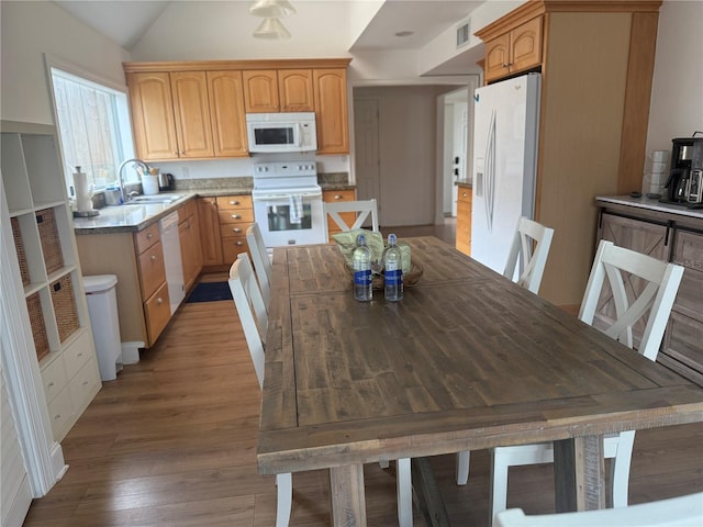 kitchen featuring hardwood / wood-style floors, light brown cabinets, white appliances, sink, and vaulted ceiling