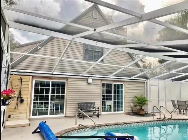 back of house featuring a patio and glass enclosure