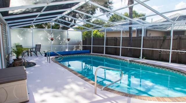 view of swimming pool featuring a lanai and a patio