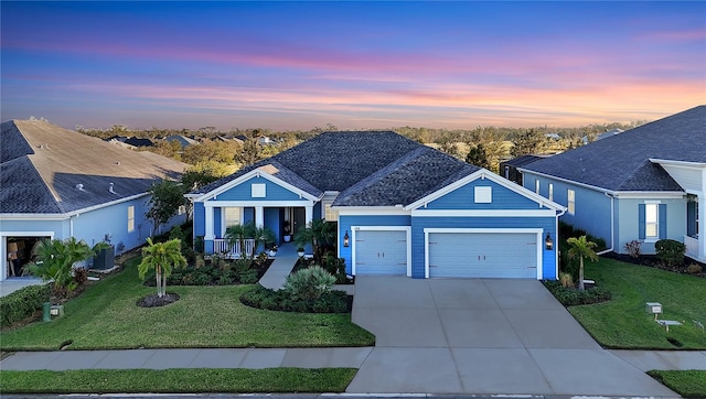 view of front of property featuring covered porch, a garage, and a yard