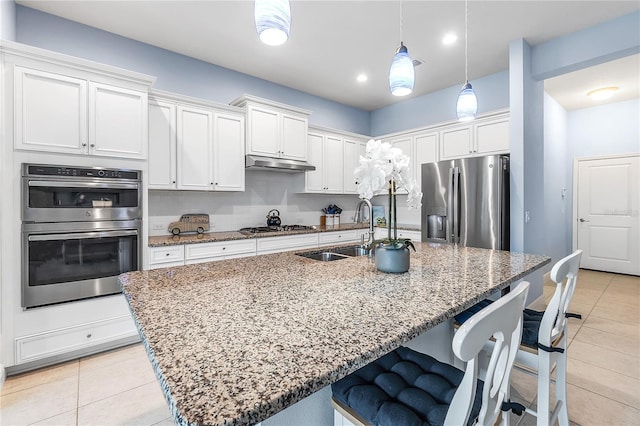 kitchen featuring white cabinets, sink, an island with sink, and stainless steel appliances