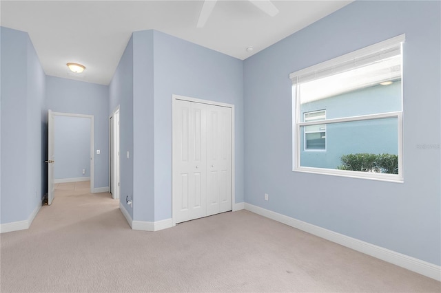 unfurnished bedroom featuring ceiling fan, light colored carpet, and a closet