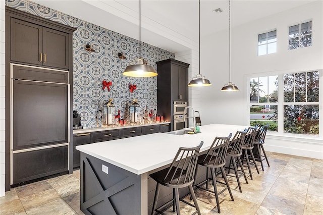 kitchen featuring sink, decorative light fixtures, a kitchen breakfast bar, and a kitchen island with sink