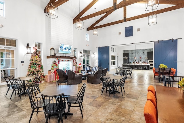 dining area featuring beam ceiling, a barn door, and high vaulted ceiling