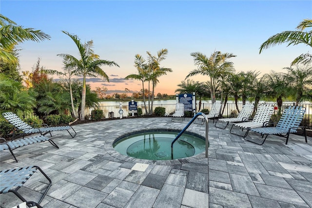 pool at dusk with a patio area and a community hot tub