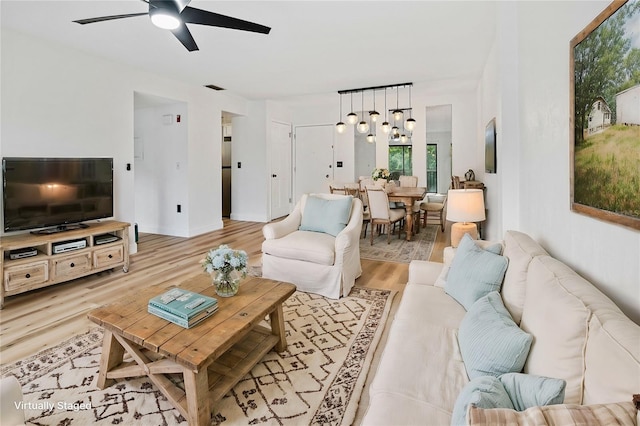 living room featuring light hardwood / wood-style flooring and ceiling fan with notable chandelier