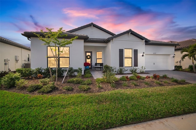 view of front of house with driveway, a garage, a lawn, and stucco siding