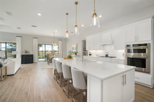 kitchen featuring a large island, decorative light fixtures, white cabinetry, and appliances with stainless steel finishes