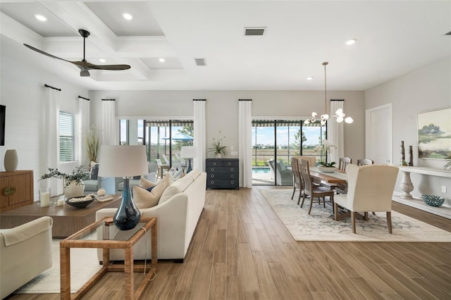 living room featuring beam ceiling, ceiling fan with notable chandelier, hardwood / wood-style flooring, and coffered ceiling