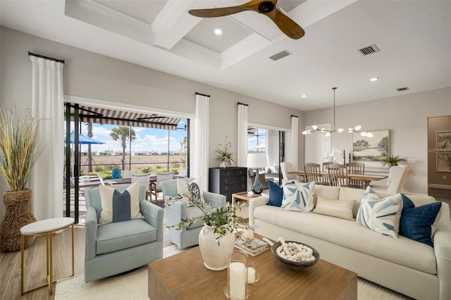 living room with ceiling fan with notable chandelier, beam ceiling, light wood-type flooring, and coffered ceiling