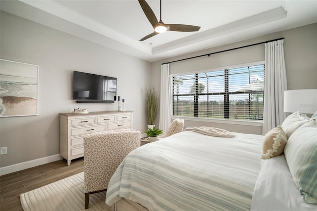 bedroom featuring ceiling fan, a raised ceiling, and ornamental molding