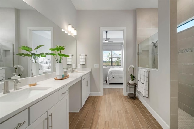 bathroom with a tile shower, vanity, and ceiling fan