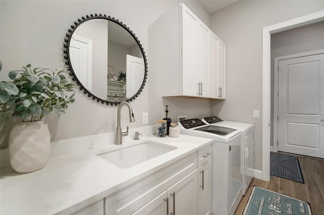 clothes washing area featuring cabinets, sink, and washing machine and clothes dryer