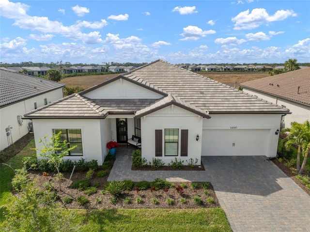 single story home with a garage, a tile roof, decorative driveway, and stucco siding