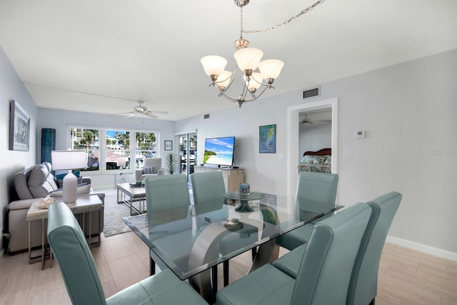 dining room with ceiling fan with notable chandelier and light hardwood / wood-style floors