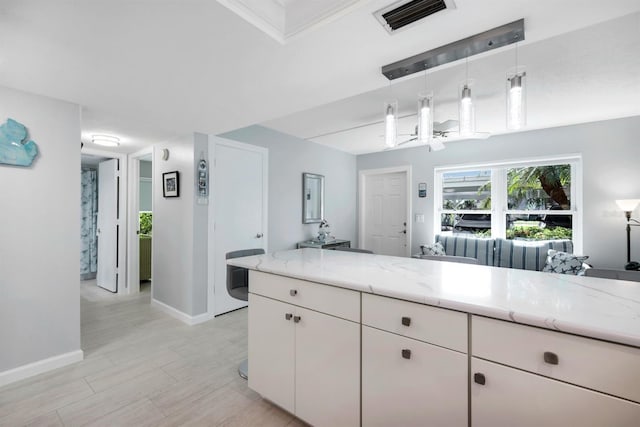 kitchen featuring white cabinets, decorative light fixtures, light stone countertops, and ornamental molding