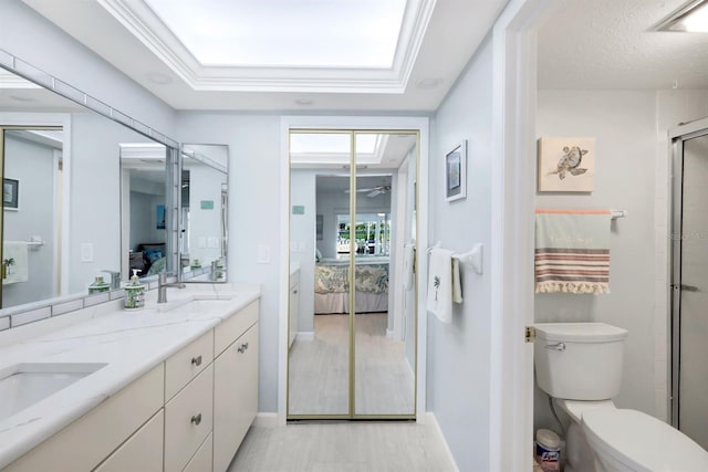 bathroom featuring vanity, a shower with door, toilet, ornamental molding, and a textured ceiling