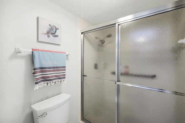 bathroom with a textured ceiling, toilet, and walk in shower