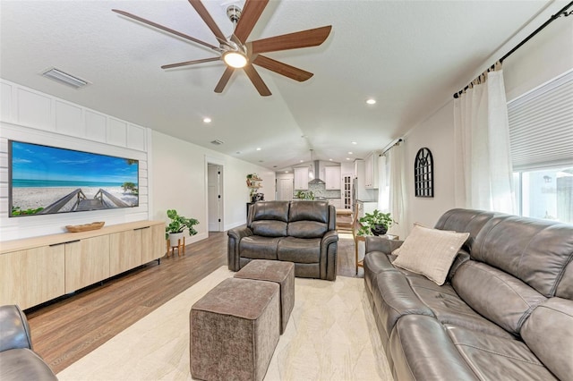 living room featuring light hardwood / wood-style floors, ceiling fan, and lofted ceiling