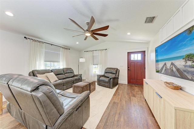 living room featuring a textured ceiling, ceiling fan, light hardwood / wood-style flooring, and vaulted ceiling