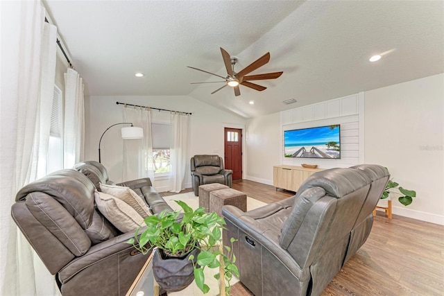 living room featuring ceiling fan, light hardwood / wood-style floors, a textured ceiling, and vaulted ceiling