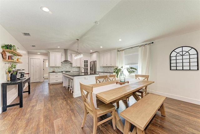 dining space featuring a textured ceiling, sink, hardwood / wood-style floors, and lofted ceiling