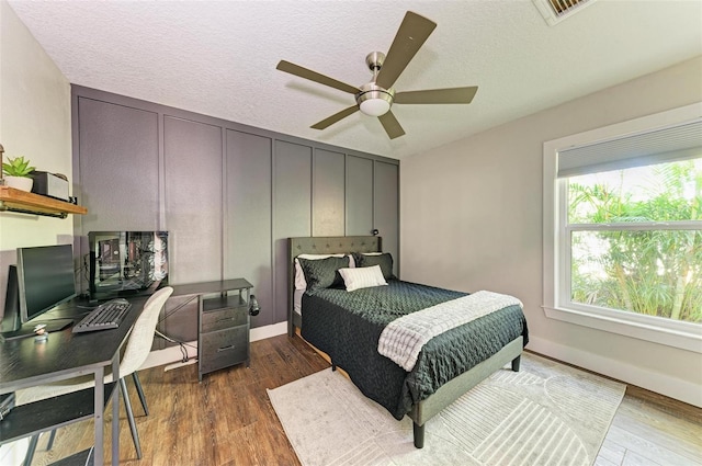 bedroom featuring a textured ceiling, dark hardwood / wood-style floors, and ceiling fan