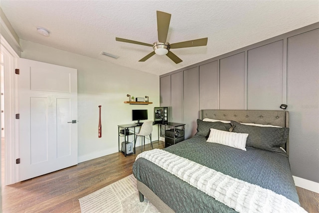 bedroom featuring wood-type flooring, a textured ceiling, and ceiling fan