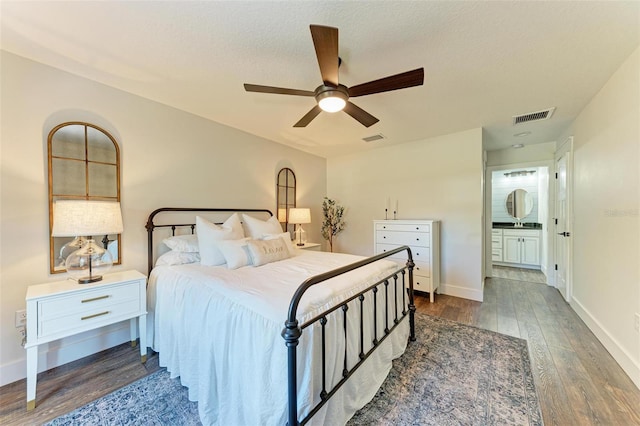 bedroom featuring a textured ceiling, ceiling fan, sink, connected bathroom, and dark hardwood / wood-style floors