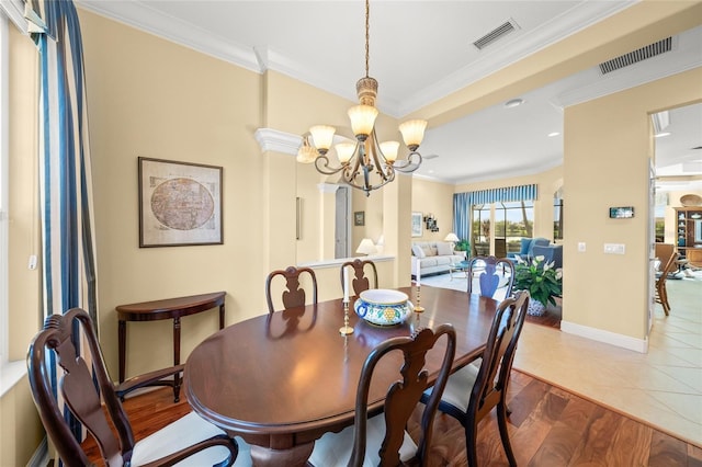 dining space with hardwood / wood-style flooring, crown molding, and an inviting chandelier