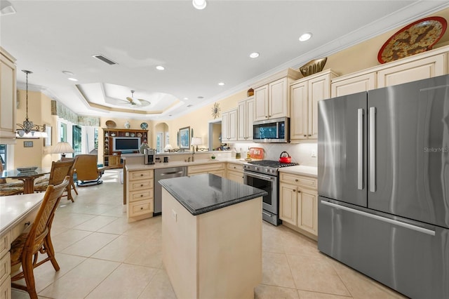 kitchen featuring kitchen peninsula, stainless steel appliances, a tray ceiling, ceiling fan, and hanging light fixtures