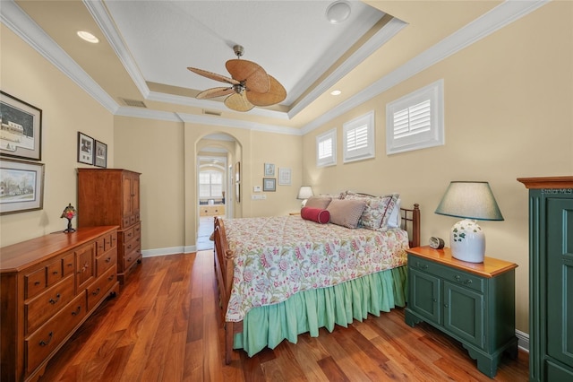 bedroom featuring dark hardwood / wood-style flooring, a tray ceiling, ceiling fan, and crown molding