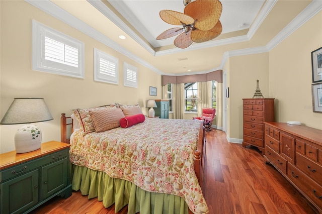 bedroom featuring ceiling fan, dark hardwood / wood-style floors, ornamental molding, and a tray ceiling