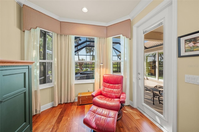 living area with crown molding, plenty of natural light, and light wood-type flooring