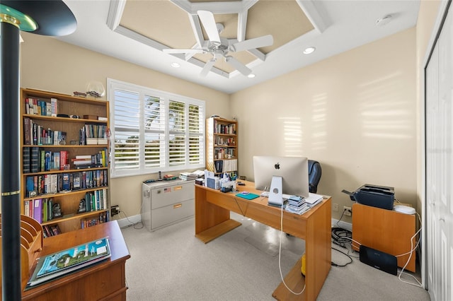 carpeted office space featuring ceiling fan and a raised ceiling