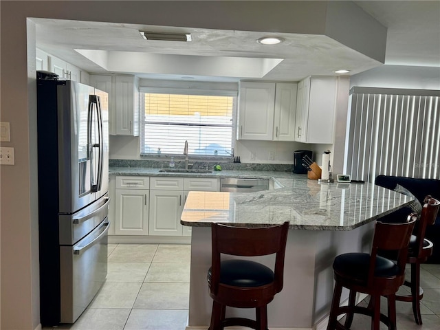 kitchen featuring white cabinets, kitchen peninsula, a breakfast bar area, and appliances with stainless steel finishes