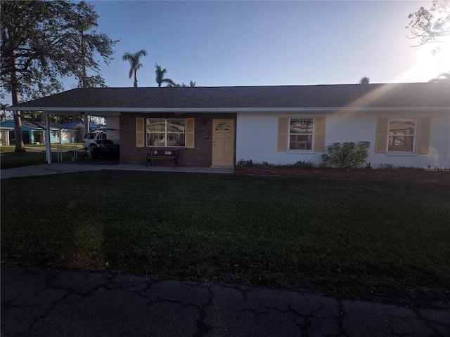 single story home featuring a lawn and a carport