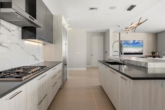 kitchen featuring extractor fan, stainless steel gas cooktop, sink, gray cabinets, and hanging light fixtures