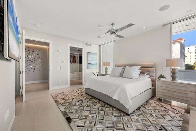 bedroom featuring ceiling fan, light hardwood / wood-style floors, a spacious closet, and a closet