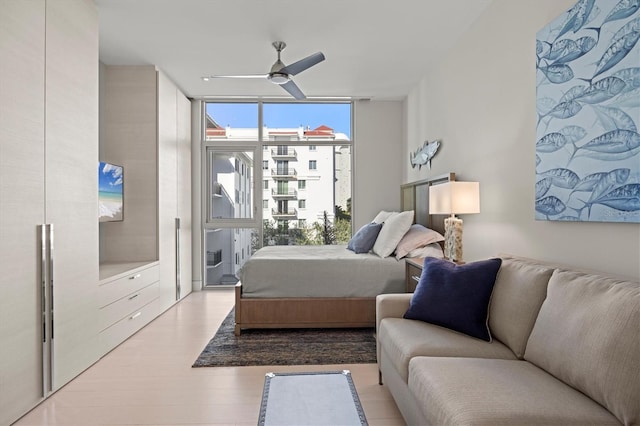 bedroom with ceiling fan, expansive windows, and light wood-type flooring