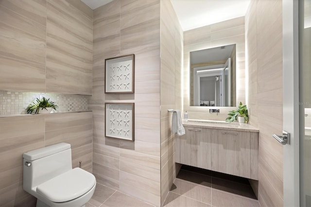 bathroom featuring tile patterned flooring, vanity, toilet, and tile walls