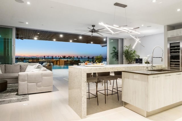 kitchen featuring a large island, sink, ceiling fan, hanging light fixtures, and a breakfast bar