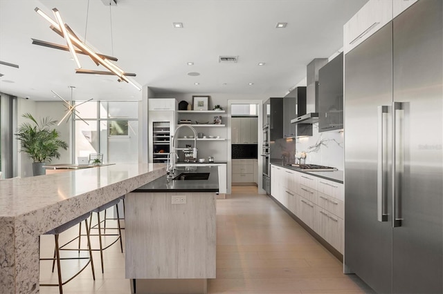 kitchen with tasteful backsplash, a breakfast bar, stainless steel appliances, a kitchen island with sink, and decorative light fixtures