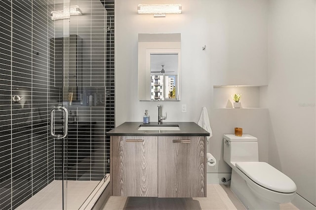 bathroom with vanity, ceiling fan, toilet, and a shower with shower door